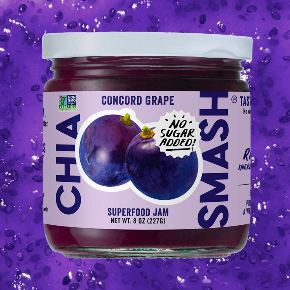 A jar of Chia Smash Concord Grape superfood jam features a purple label with images of grapes and a "No Sugar Added!" sticker, set against a vibrant purple background with chia seeds.