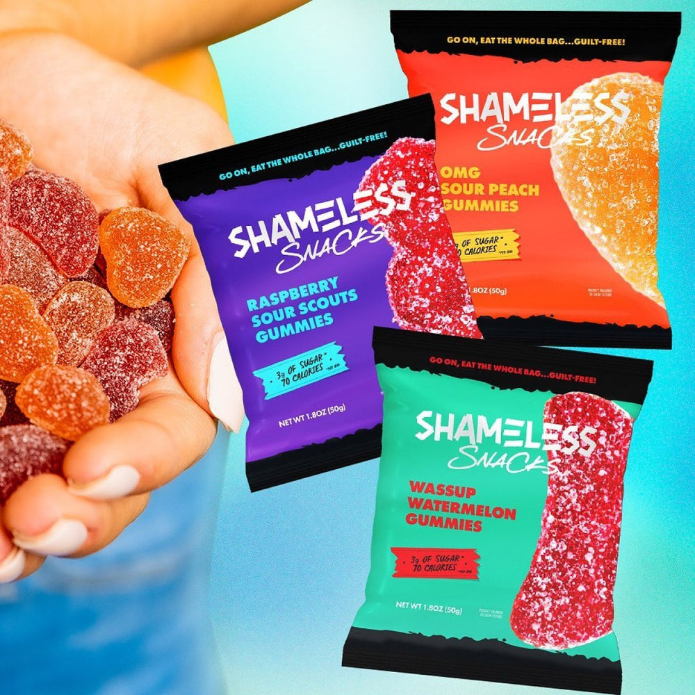 A hand holds colorful gummy candies while three vibrant packages of Shameless Snacks gummies—Raspberry Sour Scouts, OMG Sour Peach, and Wassup Watermelon—are displayed against a bright background.