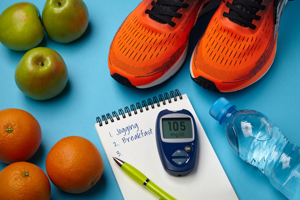 Bright orange running shoes sit next to green apples and oranges, with a notepad listing "Jogging" and "Breakfast," a blood glucose meter displaying "105 mg/dl," and a water bottle on a blue background.
