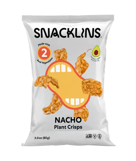 A bag of Snacklins Nacho Plant Crisps features a playful design with a cartoon mouth and crispy snacks, highlighting that it is made with two real vegetables and contains avocado oil.