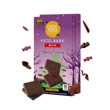 A colorful package of ChocZero Keto Bark Milk with popping candy features chocolate pieces in front, set against a whimsical purple background with Halloween-themed decorations.