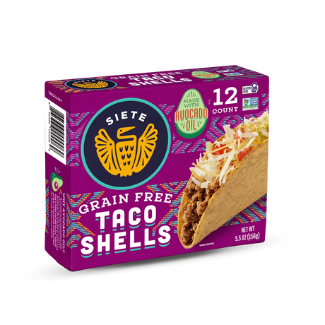 A colorful package of Siete Grain Free Taco Shells prominently displays the brand logo, highlights made with avocado oil, and shows a taco filled with meat and toppings, indicating a gluten-free product.
