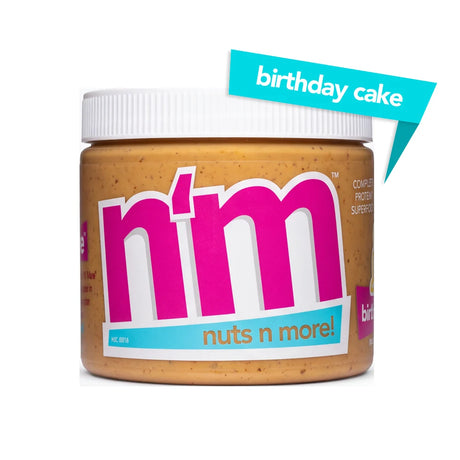 A jar of "n'm" nut butter with a birthday cake flavor label, featuring bright pink and blue text, sits against a white background, highlighting its unique flavor and protein content.
