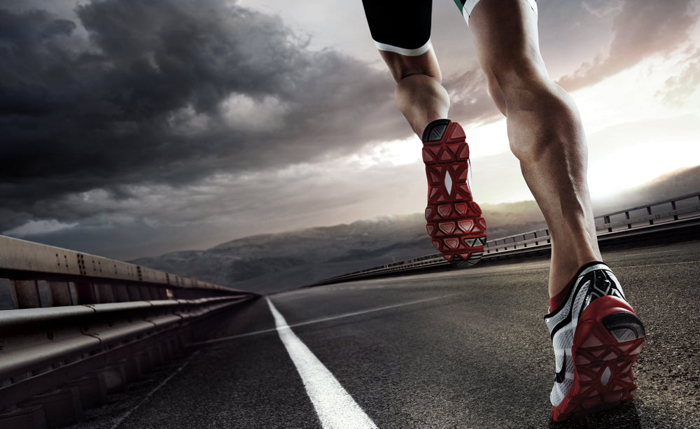 A runner in athletic gear sprints along a deserted road under a dramatic sky, showcasing determination and speed as they approach the horizon.