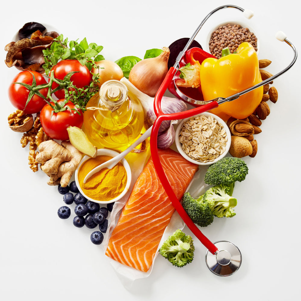 A heart-shaped arrangement of fresh foods like salmon, vegetables, and nuts is complemented by a red stethoscope, symbolizing heart health and nutrition.