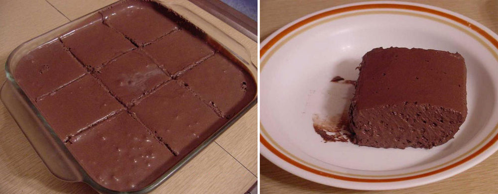 A glass dish contains neatly cut squares of chocolate fudge, while a single piece sits on a white plate with an orange rim, showcasing its rich texture and color against a wooden surface.