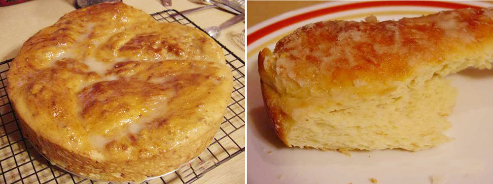 A freshly baked citrus-glazed coffee cake sits on a cooling rack, showcasing a golden-brown top with a glossy glaze, while a slice on a plate reveals its soft, fluffy interior.