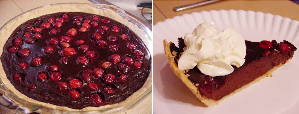 A chocolate pie topped with bright red cherries is displayed in a glass pie dish, alongside a slice of the pie on a white plate, garnished with a swirl of whipped cream.