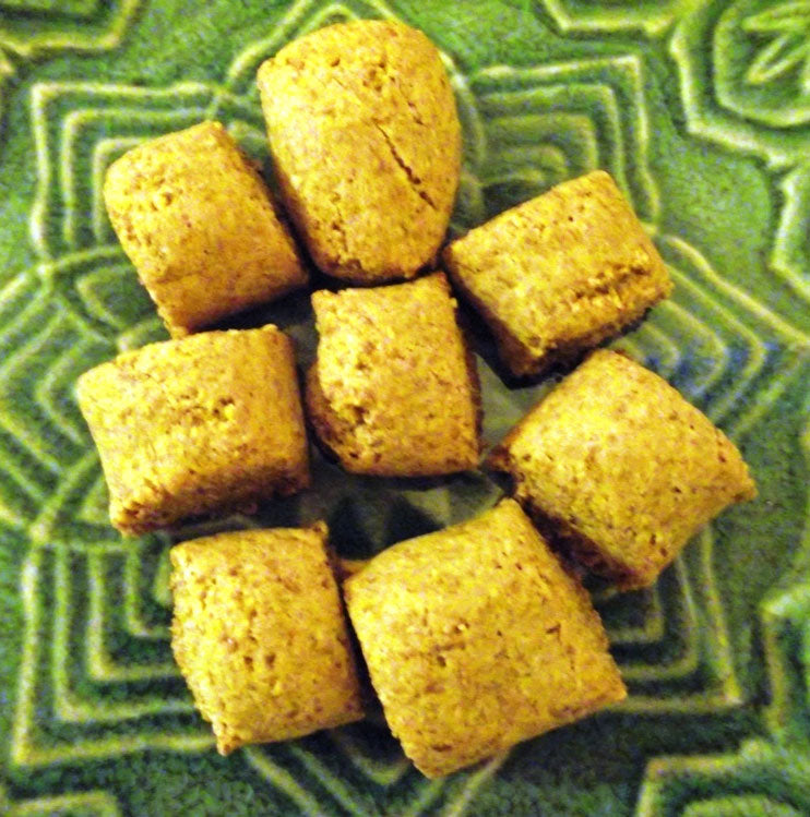 Nine golden-brown, square-shaped pieces of food are arranged in a circular pattern on a textured green plate.