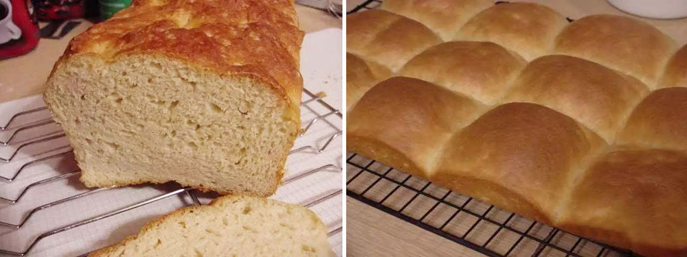 A freshly baked loaf of bread is sliced on a cooling rack next to a tray of golden brown dinner rolls, showcasing their soft texture and inviting appearance.