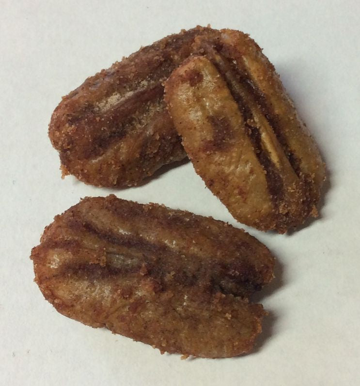 Three golden-brown, oval-shaped fried snacks with a textured surface and dark stripes are arranged on a light-colored background.