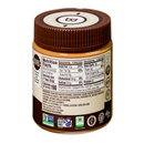A jar of almond butter with a brown lid displays the nutrition facts and ingredients label, highlighting its creamy texture and health benefits, including being gluten-free and non-GMO.