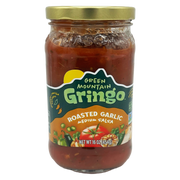 A clear glass jar of Green Mountain Gringo roasted garlic medium salsa, featuring a colorful label with images of vegetables, sits against a plain background.