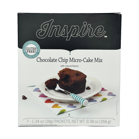 A box of Inspire Chocolate Chip Micro-Cake Mix features a slice of cake on a plate with a fork, set on a colorful heart-patterned napkin, highlighting its gluten-free and no added sugar attributes.