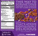 A colorful nutrition label displays calorie and ingredient information for Atkins snacks, surrounded by chocolate-covered treats, nuts, and caramel, emphasizing low sugar and high flavor.