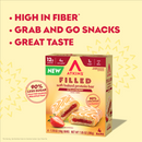 A colorful box of Atkins Filled soft baked protein bars in strawberry flavor is displayed, highlighting features like high fiber, low sugar, and great taste, with a strawberry in front for added context.