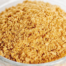 A close-up of finely ground brown sugar in a clear glass bowl, showcasing its granular texture and warm, golden-brown color.
