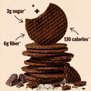 A stack of chocolate wafer cookies with a bite taken out of the top one, displaying nutritional information: 3g sugar, 6g fiber, and 130 calories per serving, alongside pieces of chocolate.