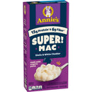 A purple box of Annie's Super Mac featuring shells and white cheddar, highlighting 15 grams of protein and 6 grams of fiber, with a spoonful of creamy pasta shown on the side.