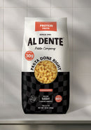 A bag of Al Dente protein pasta, featuring cavatappi noodles, displays nutritional information and cooking instructions against a light tiled background.