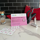 A pink product card for "Awaken Her Female Libido Patch" is displayed on a marble surface alongside a perfume bottle, red handbag, high-heeled shoe, and lipstick, highlighting its benefits for female libido support.