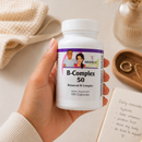 A hand holds a bottle of B-Complex 50 dietary supplement.