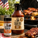 G Hughes Smokehouse sugar-free BBQ sauce and rub with a grill and food in the background