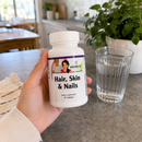 Person holding Hair, Skin & Nails by BariatricPal supplement bottle in their kitchen