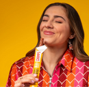 Woman enjoying a Chomps antibiotic-free turkey snack stick against a bright yellow background.