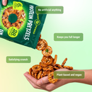 A hand pours protein pretzels from a green bag, with some pretzels falling into another hand below, highlighting benefits like being plant-based, vegan, and having no artificial ingredients.