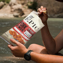 Person holding a package of Epic Pork Rinds by a river