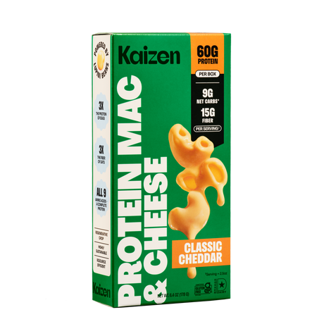 A green box of Kaizen Protein Mac & Cheese features the text "Classic Cheddar" and highlights nutritional benefits, including 60g of protein and 15g of fiber per serving, with a macaroni shape on the front.