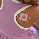 A child wearing a purple dress has a cartoon-themed bandage on her shoulder, indicating she has received a vaccination or treatment.