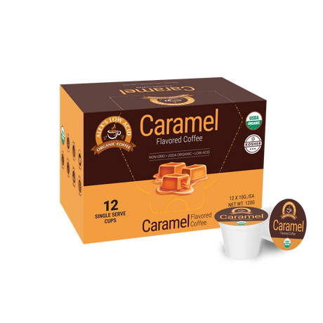 A box of caramel flavored coffee pods, featuring 12 single-serve cups, is displayed with labels indicating it's organic, non-GMO, and low acid, set against a plain background.