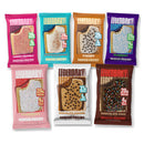 Seven colorful protein pastry packages are displayed, featuring flavors like Cherry Crumble, S'mores, and Chocolate Cake, each highlighting protein content and low sugar.