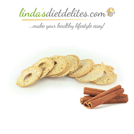 Sliced low-carb bread is arranged in a semi-circle with a few cinnamon sticks placed beside it, set against a plain background, highlighting a healthy snack option.
