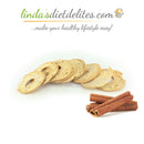 Sliced low-carb bread is arranged in a semi-circle with a few cinnamon sticks placed beside it, set against a plain background, highlighting a healthy snack option.