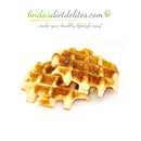 Golden-brown waffles are stacked on a white surface, showcasing their crispy texture and grid pattern, ideal for a healthy lifestyle.