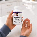 A person holds a white bottle of BariatricPal Coenzyme Methyl B-12 5,000 mcg dietary supplement in one hand while holding three pinkish-white cherry flavored chewable tablets in the other hand.