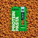 A box of Kaizen protein pasta is centered among a pile of radiatori-shaped pasta, featuring bold green packaging with nutritional information highlighting 80g of protein, 6g net carbs, and 15g fiber per serving.