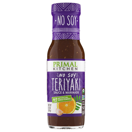 A bottle of Primal Kitchen No Soy Teriyaki Sauce and Marinade features a purple label with white text, highlighting its soy-free and no artificial sweeteners attributes, alongside an orange and garlic illustration.