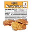 Pancakes are stacked on a surface in front of a nutrition label highlighting low carb content, with details on serving size, calories, and other nutritional information prominently displayed above.