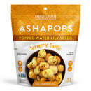 A colorful bag of Asha Pops Popped Water Lily Seeds featuring a turmeric garlic flavor, displaying a bowl of crunchy snacks on the front with labels indicating gluten-free and vegan.