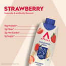 A carton of Atkins strawberry high protein shake displays nutritional information, including 15g protein, 3g fiber, 2g net carbs, and 1g sugar, with a strawberry graphic on a light background.