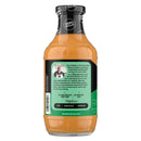 A clear bottle of Guy Hughes' zero sugar sauce features a vibrant orange color, with text highlighting its use for dipping, drizzling, or spreading, and a description of the brand's commitment to flavor and quality.