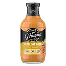 A clear bottle of G. Hughes Carolina Gold BBQ sauce features a golden-orange sauce, labeled as zero sugar, gluten-free, and low-calorie, with a serving suggestion of pulled pork on the side.