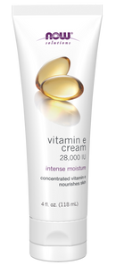 A white tube of NOW Solutions Vitamin E cream, labeled "28,000 IU" and "intense moisture," features soft gel capsules on the front, indicating concentrated vitamin E for skin nourishment.