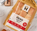 A package of Hero Hawaiian Rolls, featuring 12 soft rolls made with real butter, is displayed on a marble surface, showcasing nutritional information and a logo on the front.