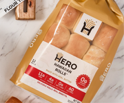 A package of Hero Hawaiian Rolls, featuring 12 soft rolls made with real butter, is displayed on a marble surface, showcasing nutritional information and a logo on the front.