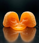 A glossy, vibrant orange egg yolk sits on a reflective black surface, flanked by two sugar-coated edges, creating a visually striking and appetizing presentation.